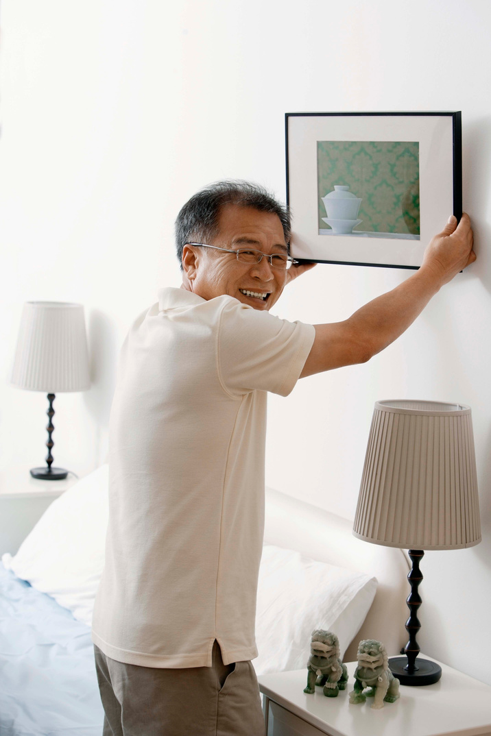 Man hanging picture on wall